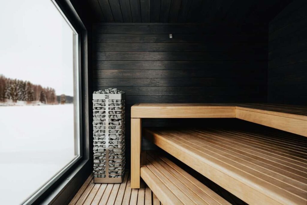 Minimalist sauna interior with large window, wooden benches, and view of snowy winter landscape