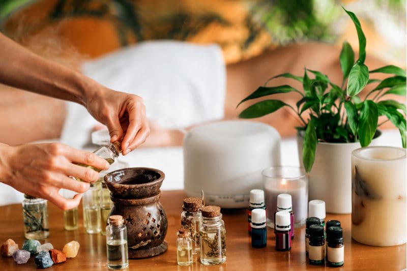 Hands adding essential oil to a diffuser, creating a relaxing atmosphere with aromatherapy.