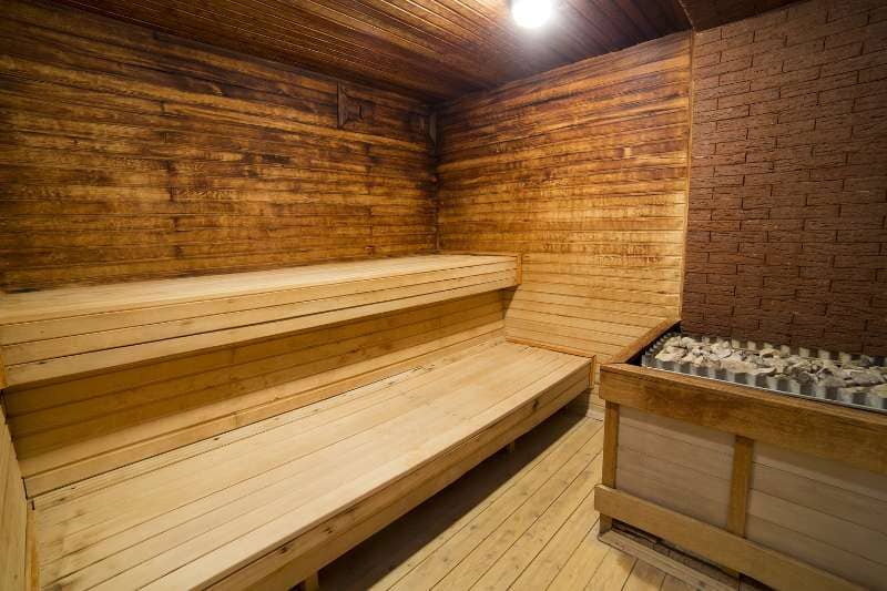 Rustic sauna interior with 2-tier sauna benches and stone heater