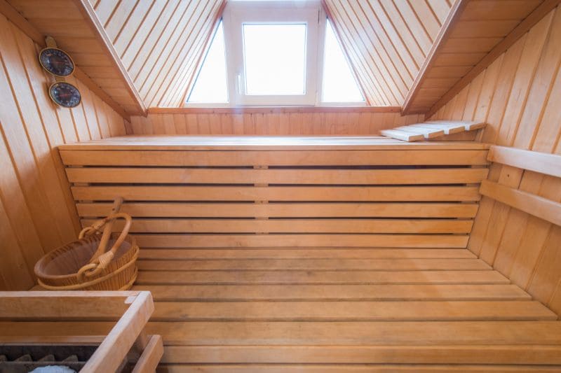 Traditional wooden sauna interior with benches and skylight window