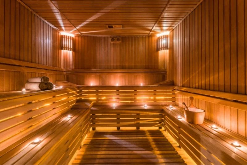 Spacious wooden sauna with ambient lighting and candles, creating a relaxing atmosphere.