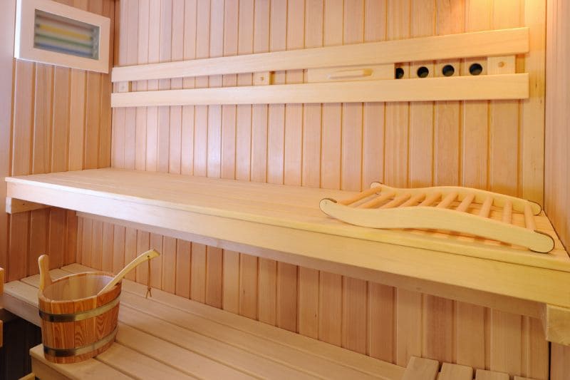 Interior of a steam room with wooden benches and a curved wooden headrest.