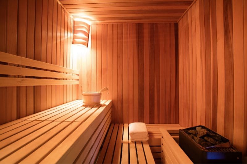 Traditional sauna interior with tiered wooden benches, vertical paneling, and warm lighting creating a cozy atmosphere