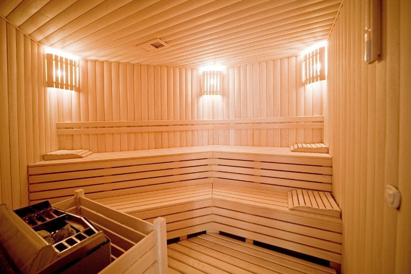 Interior view of a traditional sauna with tiered wooden benches and warm lighting.