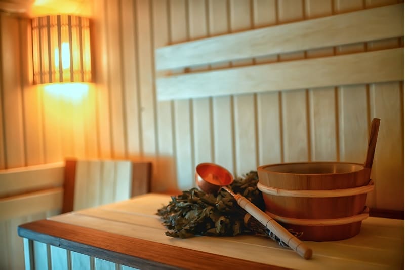 A sauna bucket and ladle with eucalyptus whisk, a natural remedy often used to help clear sinuses.