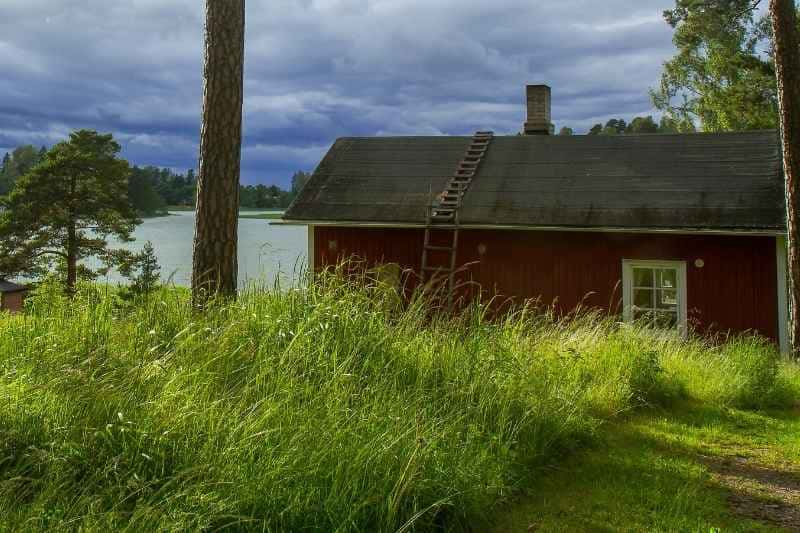 Charming Traditional Finnish Sauna House Nestled in a Picturesque Lakeside Setting, Embodying the Harmonious Integration of Saunas with Nordic Nature.