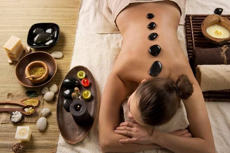 Hot stone massage setup with herbs, oils, and spa accessories for relaxation therapy