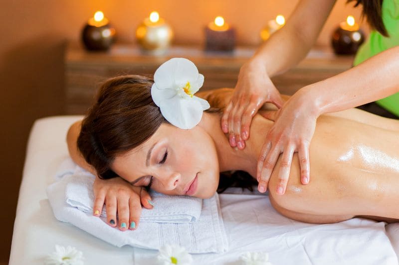 Woman receiving soothing shoulder and back massage at luxury spa with ambient candle lighting