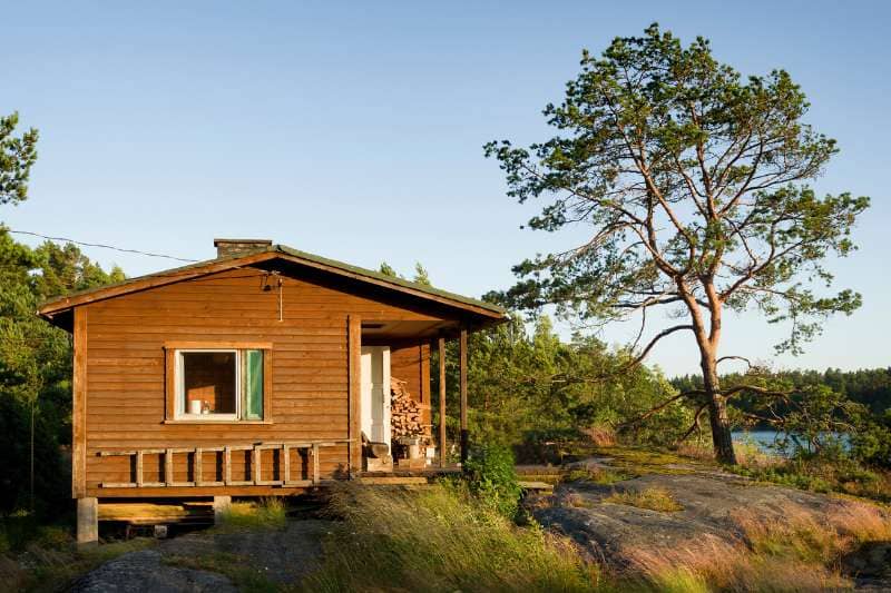 Scenic wooden sauna cottage overlooking a serene lake in a Nordic forest landscape