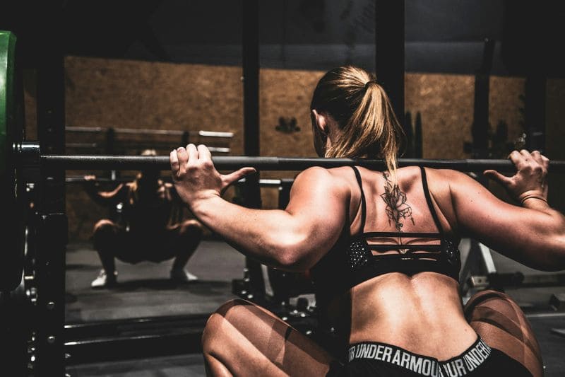 Female athlete lifting weights, demonstrating the potential for improved muscle recovery and performance when combining exercise with infrared sauna use