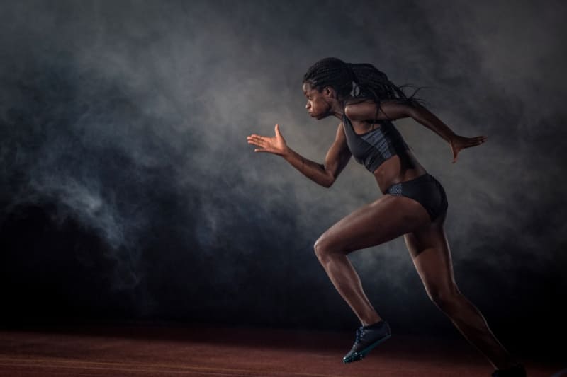 A powerful female athlete sprints on a track, highlighting the importance of recovery for optimal performance.