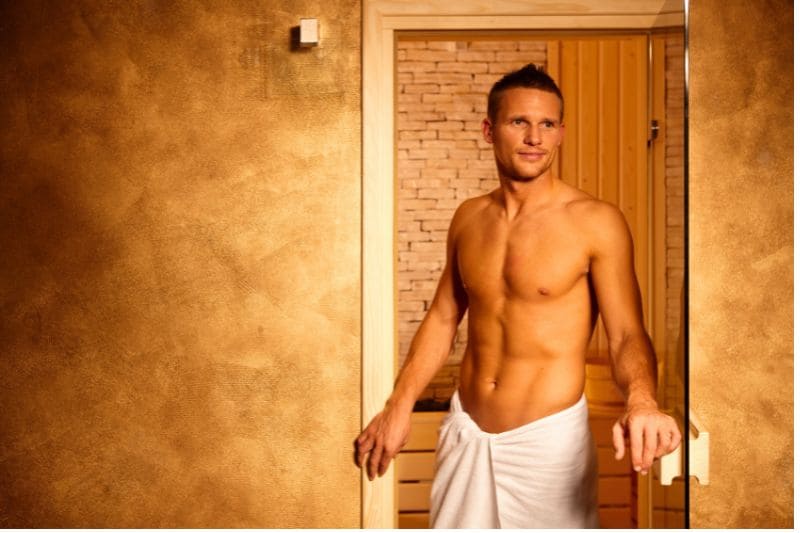 Fit man leaving sauna wrapped in towel