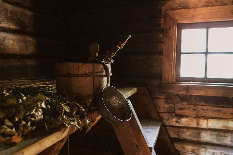 Rustic Wooden Sauna Interior with Birch Branches and Steaming Equipment, Showcasing the Traditional Sauna Rituals and Wellness Practices of Northern European Cultures.