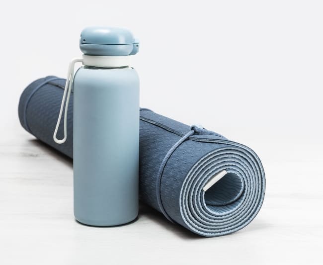 Essential exercise equipment: reusable water bottle and yoga mat for hydration and comfort