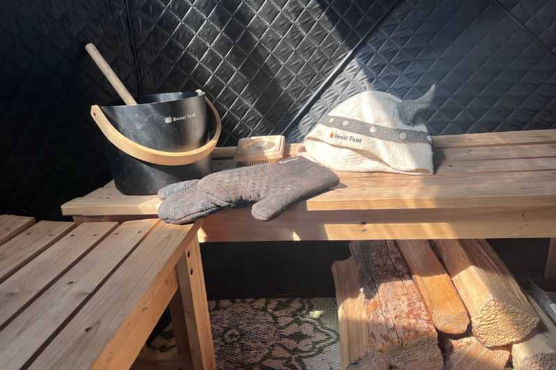 Interior of Sweat Tent Sauna with bench, bucket, ladle, and sauna hat, showcasing equipment