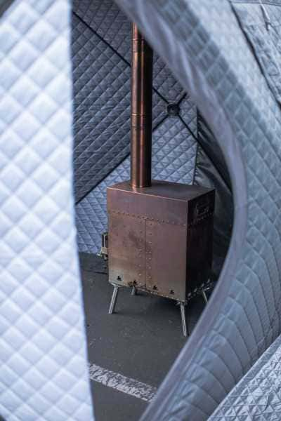 Inside view of sweat tent showing portable wood-burning stove