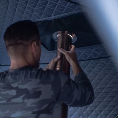 User installing stove pipe in Sweat Tent Sauna, demonstrating setup process