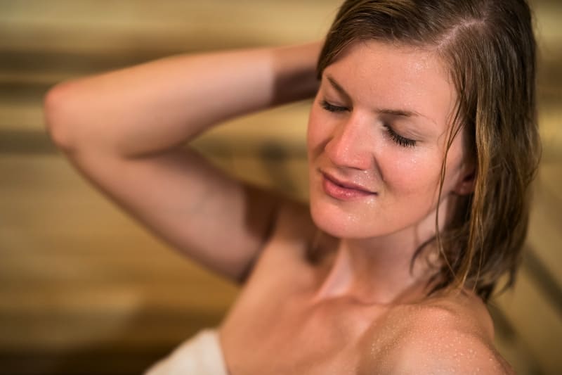 Woman with closed eyes relaxing and sweating in sauna