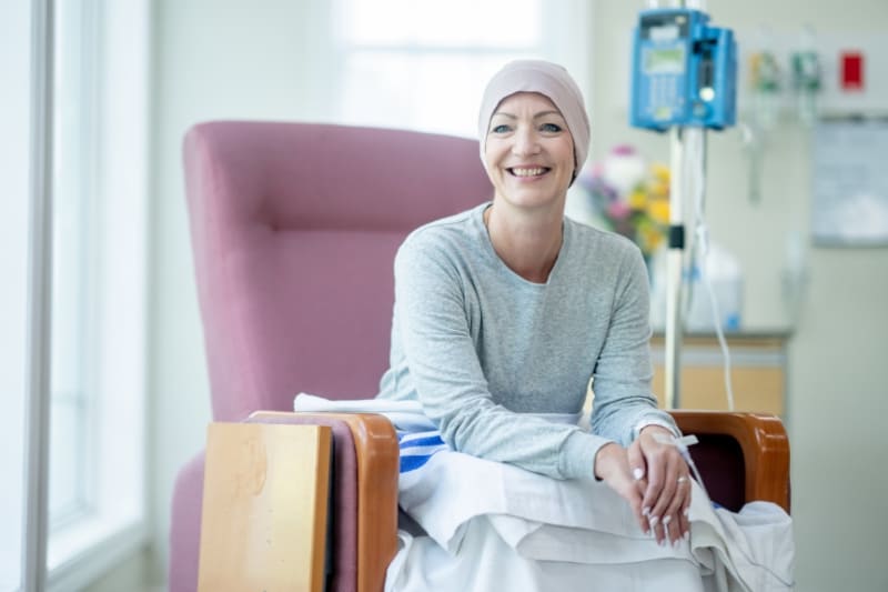 Smiling cancer patient receiving treatment in a clinical setting.