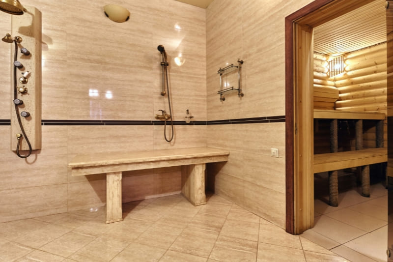 Gym sauna facility with adjacent shower area and wooden sauna entrance