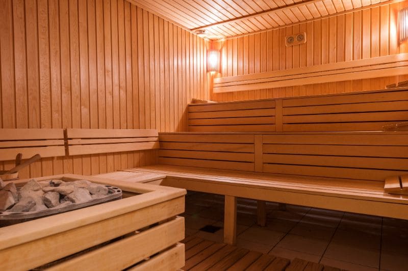 Modern sauna design with multi-level wooden benches, built-in lighting and traditional stone heater arrangement