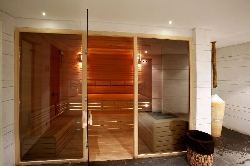 Interior of a modern wooden gym sauna with glass doors and bench seating