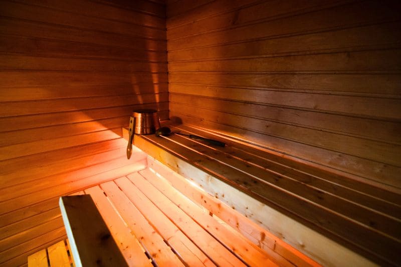 Interior view of wooden sauna benches with traditional metal bucket and ladle for the purpose of throwing water on the rocks