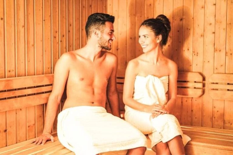 Smiling couple enjoying traditional wooden sauna, promoting relaxation and potential health benefits