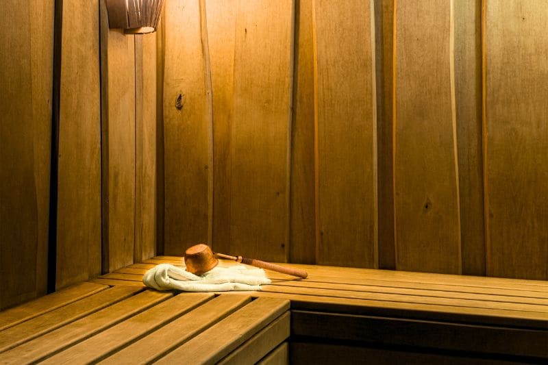 Traditional wooden sauna bench with a towel and ladle.