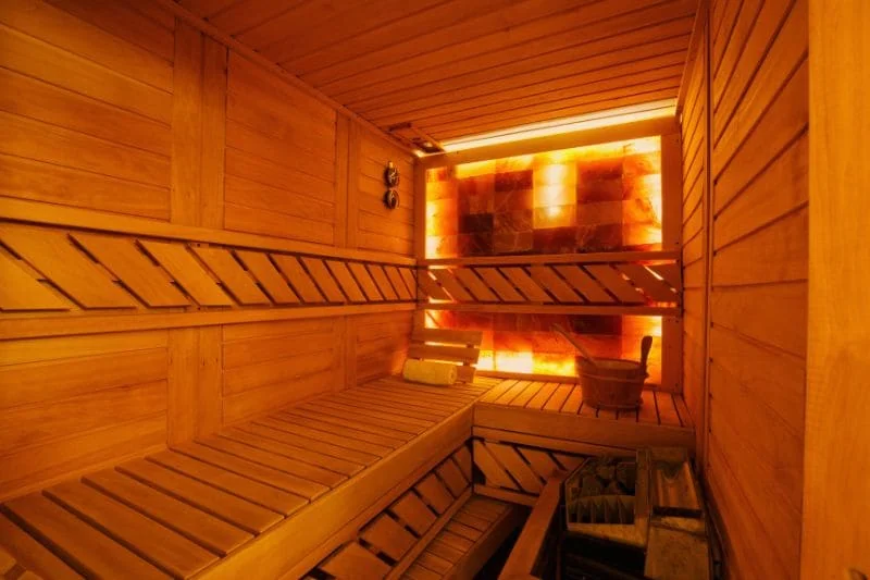 Wooden sauna interior with heated rocks and salt wall showing ideal sauna setup for relaxation