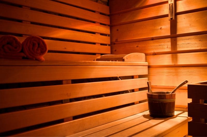 A cozy sauna featuring neatly stained wood paneling and soft, glowing lighting for a relaxing atmosphere.