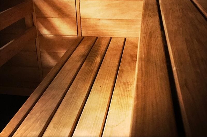 A close-up view of a sauna bench with smooth wooden panels, showcasing a professional staining job.