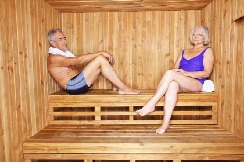 Senior couple relaxing in wooden sauna for arthritis pain relief and joint therapy