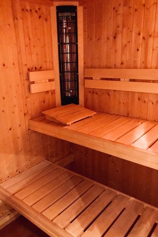 Interior of infrared sauna with built-in infrared heating panel, wooden benches, and light pine wood paneling