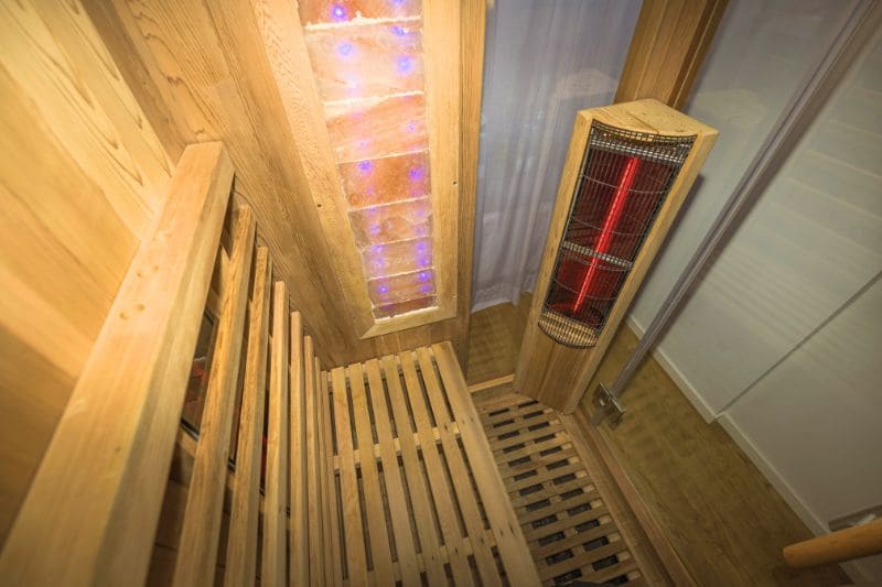 Interior view of an infrared sauna showing wooden bench seating and infrared heating panels