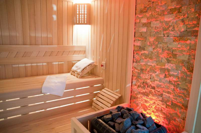 Modern sauna interior with therapeutic red light and Himalayan salt wall