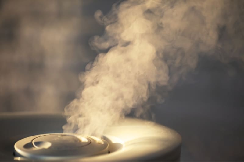 Close-up of steam rising from spa humidifier in a steam sauna with warm ambient lighting