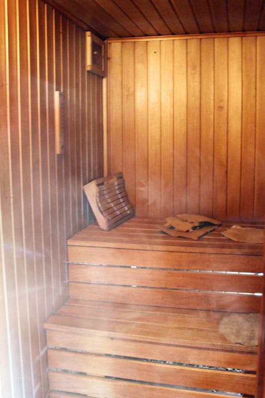 Interior of a steam sauna showing tiered wooden bench seating and natural wood wall paneling