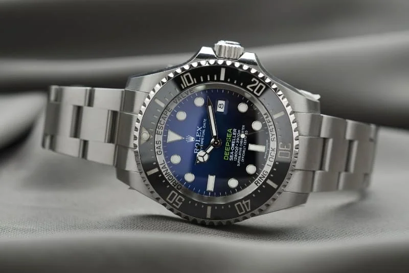 Professional diving watch with blue-black dial and stainless steel bracelet photographed on gray fabric