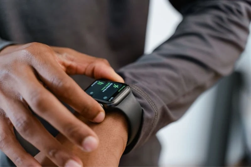 Close-up of a man checking his dark-colored smartwatch display while wearing a gray sleeve