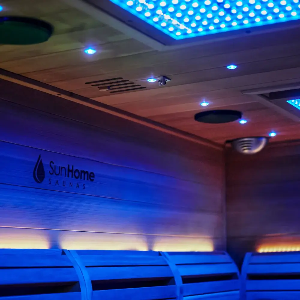 Interior ceiling detail of Sun Home Luminar 5-person outdoor infrared sauna showing LED lighting system, speakers, and brand logo under blue illumination