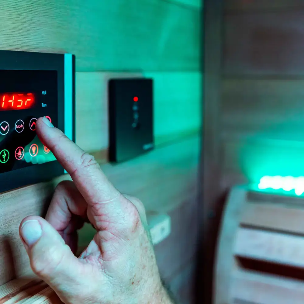 Digital control panel of Sun Home Luminar outdoor 5-person full spectrum infrared sauna showing temperature display and mode settings with LED backlit buttons under green ambient lighting