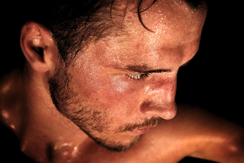 Close-up of perspiring face during intense thermal therapy session showing natural cooling response