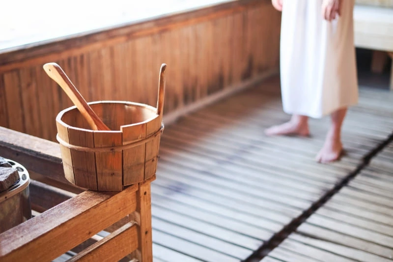 Traditional wooden sauna bucket and ladle set on cedar bench, essential accessories for DIY sauna construction