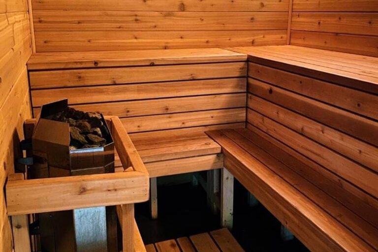 Traditional Finnish sauna interior with wooden benches and an electric heater, showing classic cedar wood paneling and multi-level seating