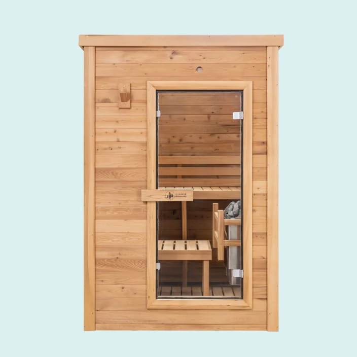 Redwood Outdoors 3-person indoor sauna with glass door showing interior benches and an electric heater with rocks on top, against a blue background