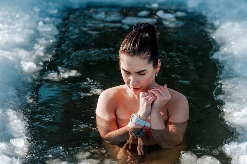 Woman in ice bath after a sauna session, showing dangerous temperature shock risks from extreme temperature changes