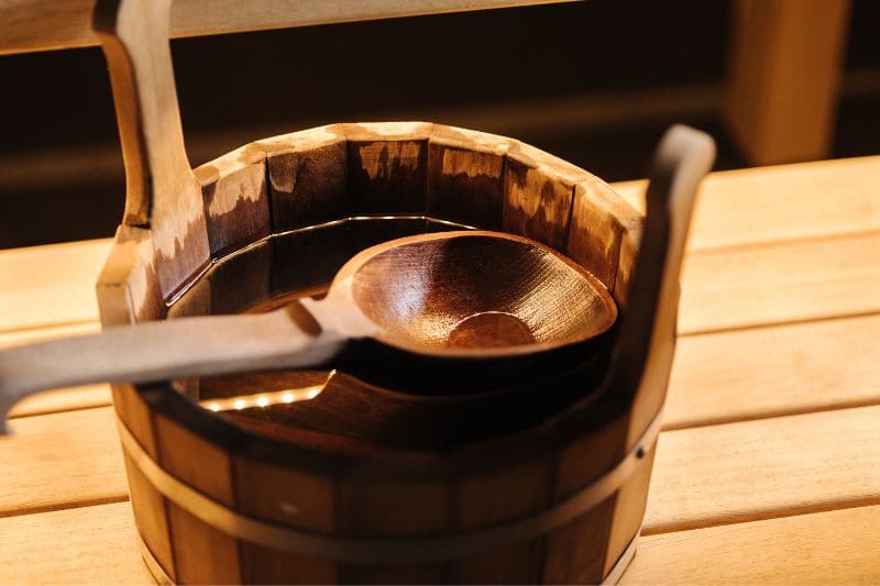 Traditional wooden sauna bucket with ladle containing water for creating steam