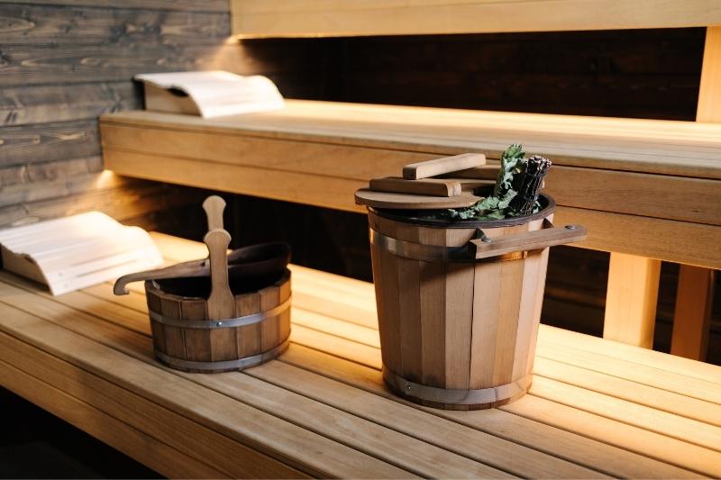 Two wooden water buckets with ladles on traditional sauna wooden benches