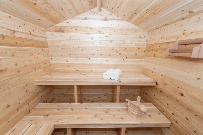 Cedar bench configuration inside Dundalk CT Georgian traditional Finnish sauna with two towels, a wooden bucket and a ladle.